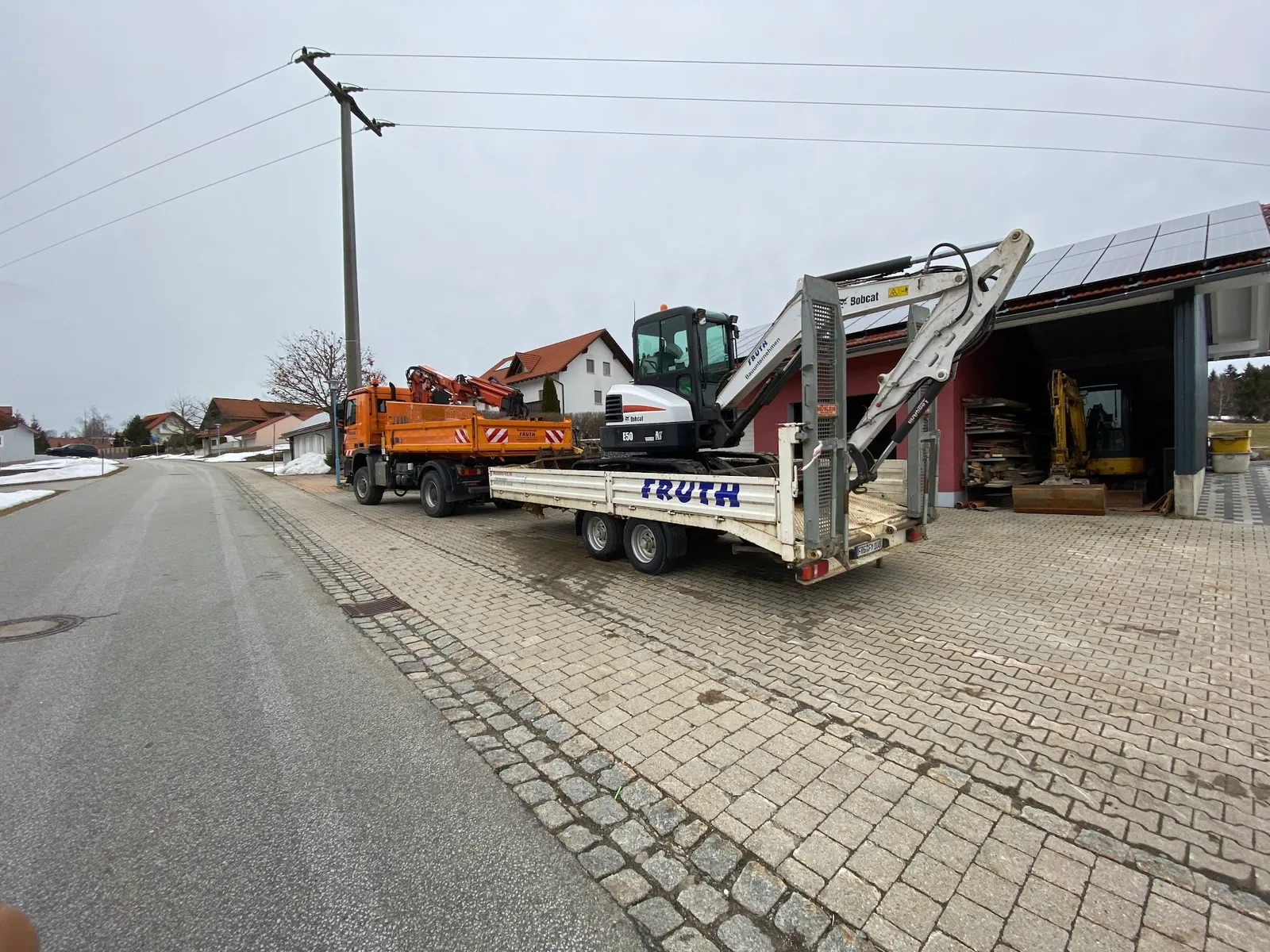 Fruth Kipper-LKW mit Bobcat E50 Bagger auf Anhänger vor dem Betriebshof