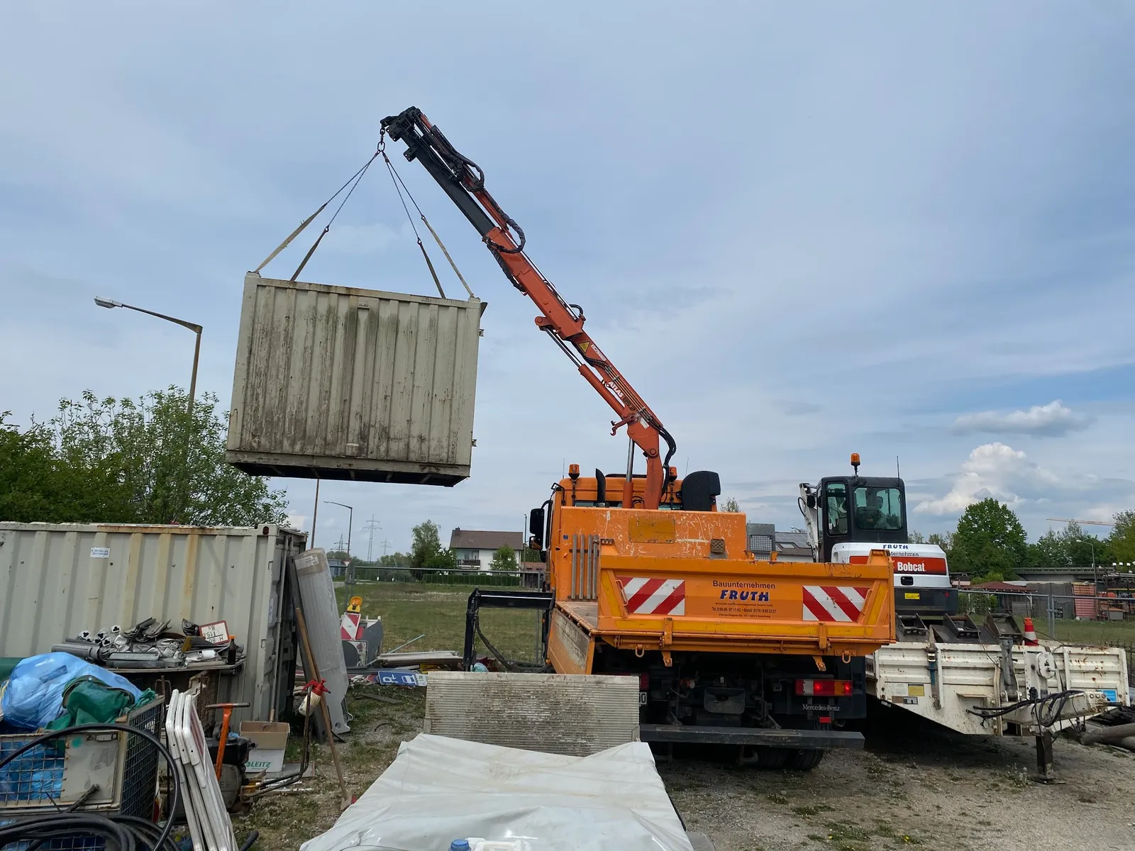 Fruth LKW mit Atlas-Kran beim Versetzen eines Baucontainers