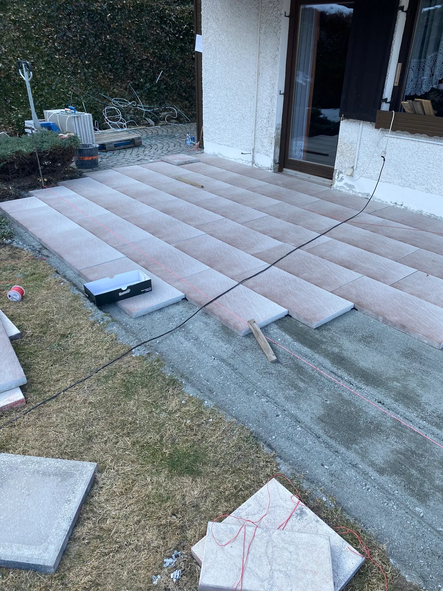 Präzise Verlegung von großformatigen Platten auf Terrasse mit Richtschnur