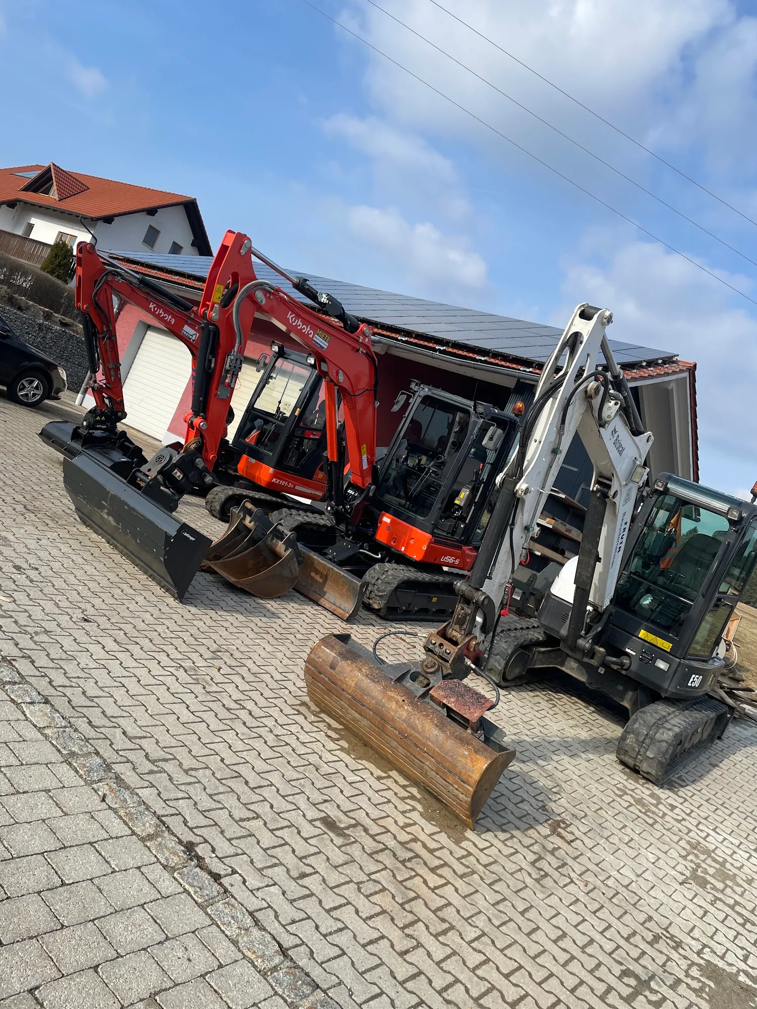 Kubota und Bobcat Kompaktbagger von Fruth aufgereiht auf gepflastertem Hof